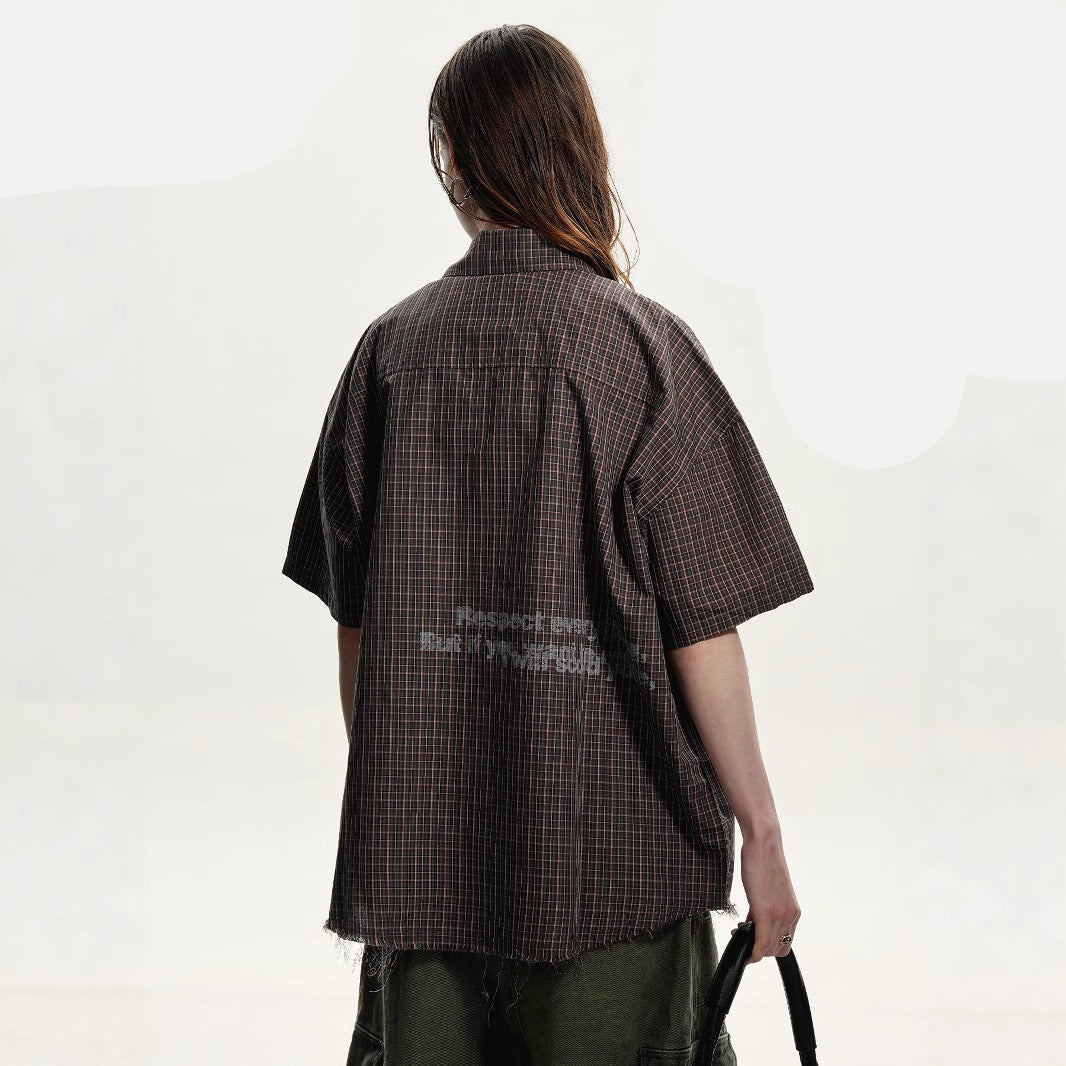 Person wearing a brown checkered shirt with text on the back, on a white background