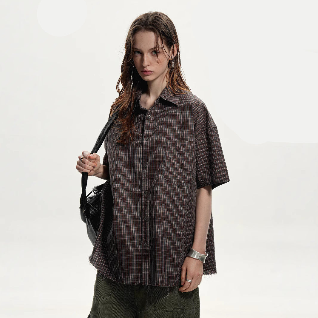 Woman wearing a plaid shirt holding a black bag on a white background with brand logos.